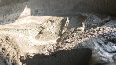 İnşaat işçisi ya da sıva işçisi inşaat alanındaki kovaya karışık beton döküyor. İnşaat konsepti.