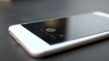 Akıllı telefon gelen bir arama ile masaya konur ve ekrandaki Reddet tuşuna basan kadının parmağı. Teknoloji ve İletişim kavramları.