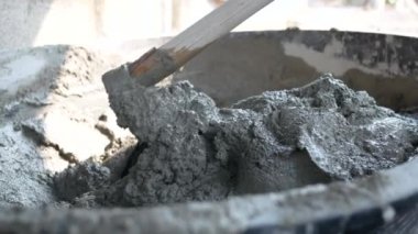 İnşaat işçisi veya sıva işçisi inşaat alanındaki plasttik pikapta çimento ve kumu karıştırmak için çapa kullanıyor. İnşaat konsepti.