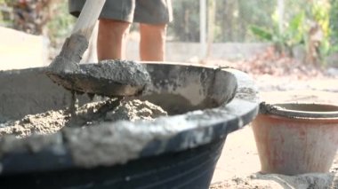 İnşaat işçisi ya da sıva işçisi inşaat alanındaki kovaya karışık beton döküyor. İnşaat konsepti.
