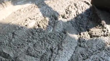 İnşaat işçisi veya sıva işçisi inşaat alanındaki plasttik pikapta çimento ve kumu karıştırmak için çapa kullanıyor. İnşaat konsepti.