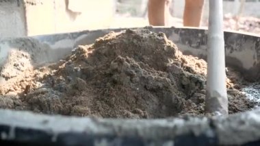 İnşaat işçisi veya sıva işçisi inşaat alanındaki plasttik pikapta çimento ve kumu karıştırmak için çapa kullanıyor. İnşaat konsepti.