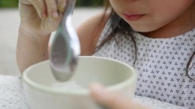 Küçük tatlı Asyalı kız Tayland böreği mi yiyor yoksa evin önündeki mermer masada hindistan cevizi sütüyle şamandıra mı yiyor?.