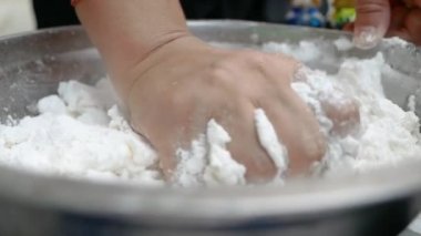 Asyalı genç bir kadın Tayland usulü tatlı ya da Şamandıra tatlısı yapıyor. Unu hindistan cevizi sütüyle karıştırma ve mangırı yoğurup şamandıra köftesi yapma sürecine yakın çekim.