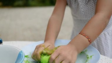 Asyalı genç kız Tayland böreği ya da Şamandıra tatlısı yapıyor. Çocuk yeşil glutinous pirinç hamuru hazırlıyor ve hindistan cevizi sütü ve şekerle kaynatılmadan önce şamandıra toplarını kaseye koyuyor..