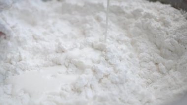 Asyalı genç bir kadın Tayland usulü tatlı ya da Şamandıra tatlısı yapıyor. Unu hindistan cevizi sütüyle karıştırma ve mangırı yoğurup şamandıra köftesi yapma sürecine yakın çekim.