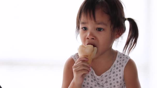 可愛いですアジアの女の子楽しみますとともに食べるアイスクリームとずさんな口 白の背景に孤立 — ストック動画