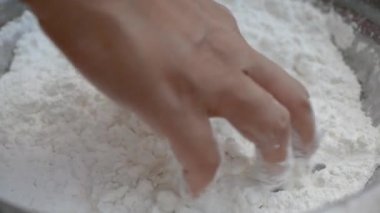 Asyalı genç bir kadın Tayland usulü tatlı ya da Şamandıra tatlısı yapıyor. Unu hindistan cevizi sütüyle karıştırma ve mangırı yoğurup şamandıra köftesi yapma sürecine yakın çekim.