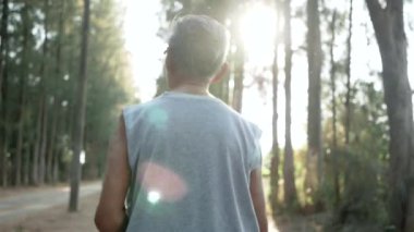 Asyalı son sınıf öğrencisi gün batımında gökyüzü arka planında parkta koşuyor. Sağlıklı yaşam tarzı ve sağlık hizmeti kavramı.