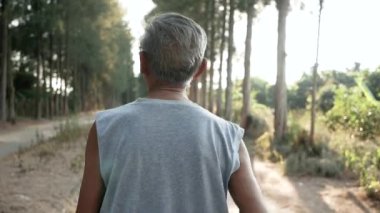 Asyalı son sınıf öğrencisi gün batımında gökyüzü arka planında parkta koşuyor. Sağlıklı yaşam tarzı ve sağlık hizmeti kavramı.