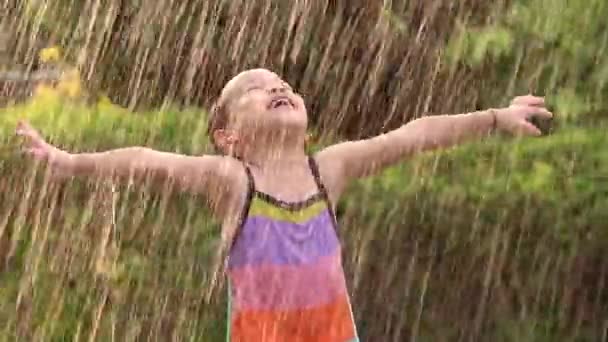 裏庭で雨が降っているかわいい女の子 暑い夏の日には屋外アクティビティを楽しむ — ストック動画