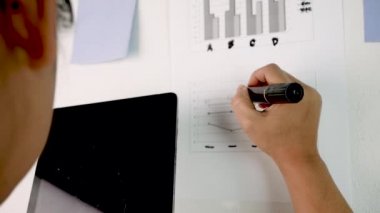 Kendine güvenen Asyalı kadın iş planı yazıyor ve fikirlerini elinde tabletle beyaz tahtaya koyuyor. Ofiste düşünen ve notlar alan bir kadın..