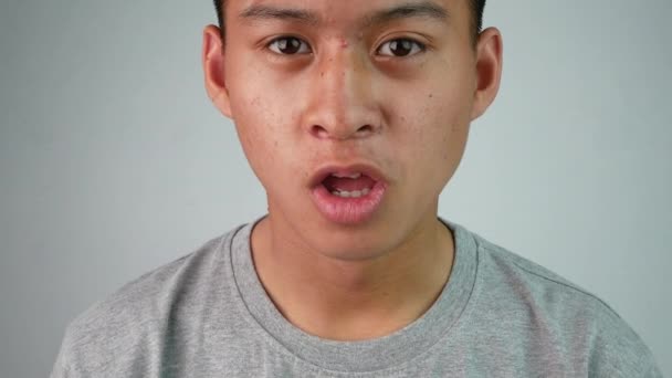Gri Tişörtlü Asyalı Genç Adam Gri Arka Planda Gördüğü Şey — Stok video