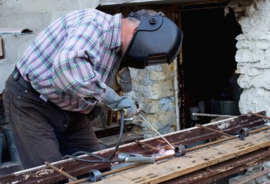 Endüstride çalışmak. Bir adam kaynak makinesiyle çalışır.