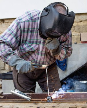 Endüstride çalışmak. Bir adam kaynak makinesiyle çalışır.