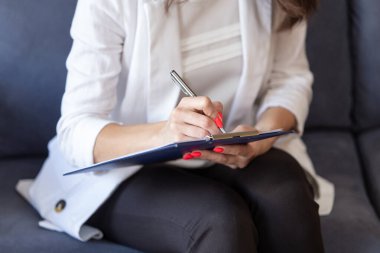 Günlük kıyafetli bir kadının elindeki not defterine yakın çekim.