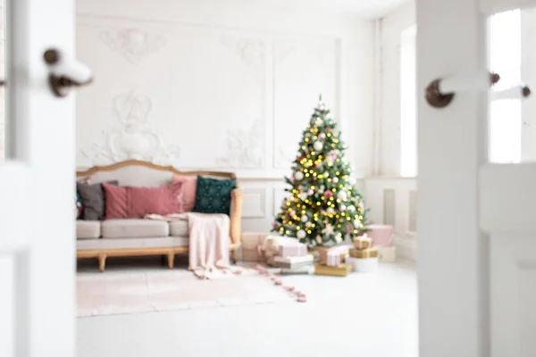 Blurred photo of white sofa standing next to christmas tree surrounded by gift boxes — Stock Photo, Image