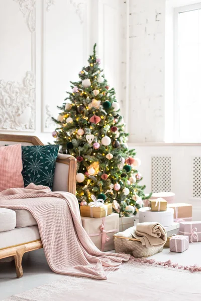 Árbol de Navidad decorado con guirnalda y cajas de regalo se encuentra cerca del sofá — Foto de Stock