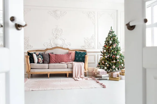 Λευκός καναπές δίπλα στο χριστουγεννιάτικο δέντρο που περιβάλλεται από κουτιά δώρων. Επιλεκτική εστίαση — Φωτογραφία Αρχείου