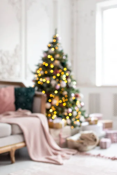 Μπλε φωτογραφία διακοσμημένο με γιρλάντα και παιχνίδια χριστουγεννιάτικο δέντρο στέκεται δίπλα σε λευκό καναπέ. — Φωτογραφία Αρχείου