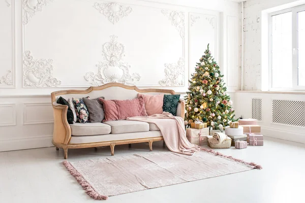 Árbol de Navidad rodeado de cajas de regalo se encuentra cerca del sofá en la sala de estar — Foto de Stock