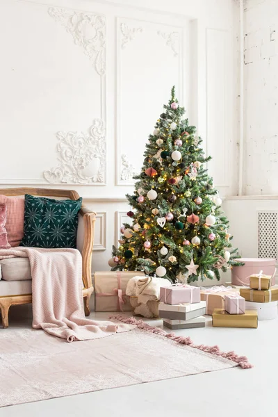 Árbol de Navidad decorado con guirnalda y cajas de regalo se encuentra cerca del sofá — Foto de Stock