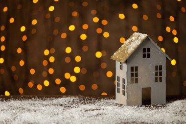 Arka planda çelenk olan tahta masanın üzerinde duran kağıt oyuncak evi. Seçici odak