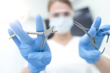 Beyaz maskeli doktorun elindeki aletlerin yakınlaştırılması. Seçici odak