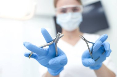 Beyaz maskeli doktorun elindeki aletlerin yakınlaştırılması. Seçici odak