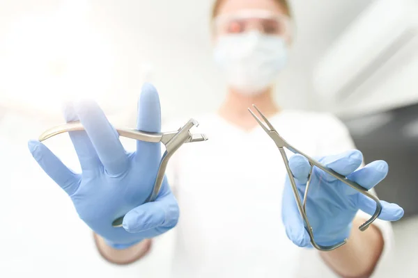 Closeup of instruments in hands of doctor in white mask. Selective focus — Stock Photo, Image