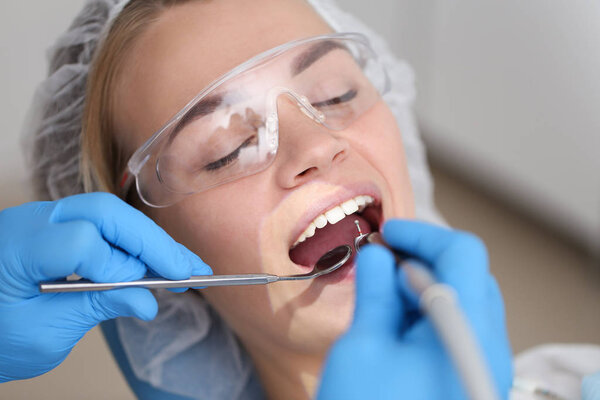 Cute woman sits in stomatologist chair and undergo checkup. Selective focus.