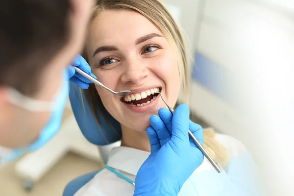 Blond female sits in dentist chair and undergo dentist checkup. Selective focus — Stock Photo, Image