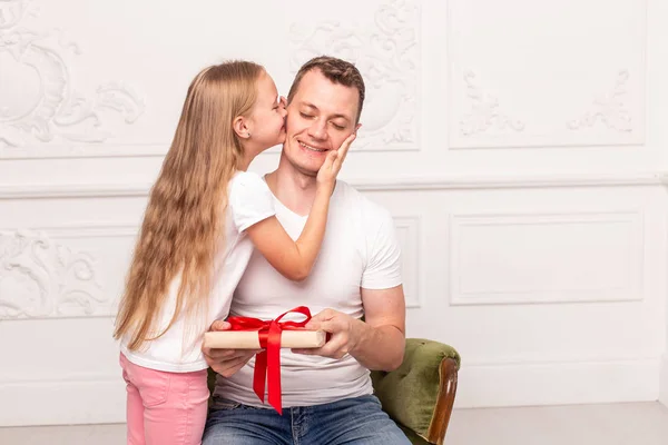 Το κοριτσάκι φιλάει τον πατέρα της, που κρατάει το κουτί δώρου στο χέρι, στο μάγουλο. Επιλεκτική εστίαση — Φωτογραφία Αρχείου