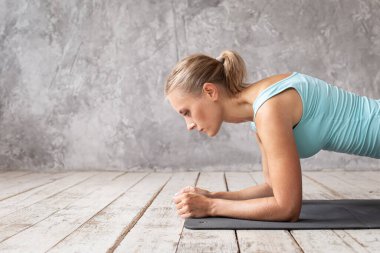 Spor elbiseli, sarışın, tatlı bir kadın. Sırtını tahtada eğitiyor.