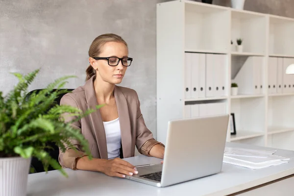 Mujer rubia en gafas trabajando con lapatop. Trabajador de oficina — Foto de Stock