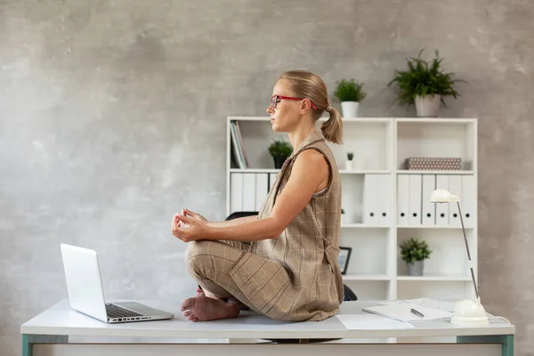 Genç işgüzar kadın masaya oturur ve meditasyon yapar.