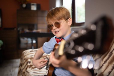 Evde gitar çalan küçük çocuk, evde kal, evde gitar çalmayı öğren.