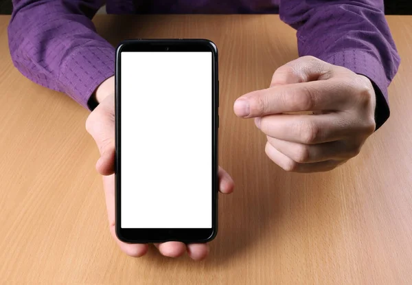 Man holds a smartphone in his hand and shows his screen to the viewer. He offers to see something on the screen and points it with his finger. The place to insert the mockup