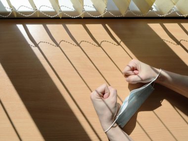 Eller yumruklara sıkıca bağlanır ve tıbbi bir maskeyle örgü şeklinde bir gölgenin arkasına bağlanır. Salgın sırasında karantina altındaki bir evde hapsedilme kavramı