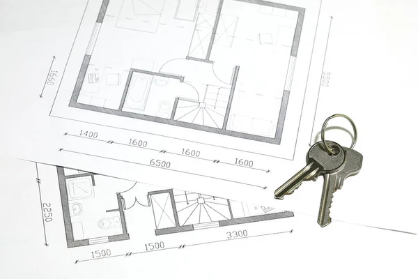 Two keys on the ring are located on sheets with fragments of the architectural housing floor plan
