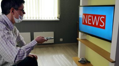 İnsan evde kalır ve salgın durumuyla ilgili olarak televizyonda hangi haberlerin yayınlanacağını bekler. Büyük harflerle yazılmış yeni yazılar ekranda görünür.
