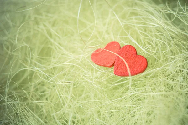 Красные деревянные сердца на зеленом фоне сизаля — стоковое фото