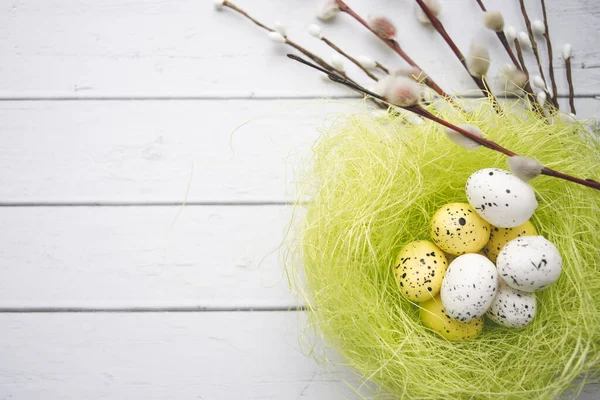 Påskpynt. Willow kvistar och dekorativa ägg i bon på trä bakgrund — Stockfoto