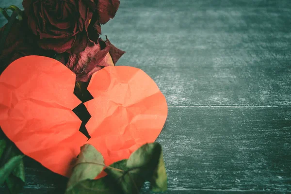 Концепция развода - красное разбитое сердце со старой розой на деревянном фоне. — стоковое фото