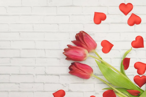 I fiori rossi tulipani e cuori su uno sfondo bianco di muro di mattoni, primavera e vacanze, Festa della Donna — Foto Stock