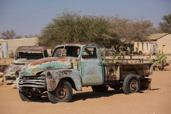 Övergiven gammal rostig förstörd historisk bil nära en bensinstation i Solitaire i Namibia öknen öra Namib-Naukluft nationalpark. Stockbild