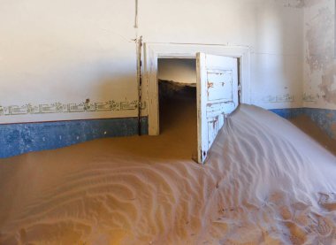 Terk edilmiş ve unutulmuş bina ve oda insanlar tarafından terk edilmiş ve işgal edilen kum fırtınası, Kolmanskop hayalet kasabası, Namib Çölü tarafından ele geçirilmiş.