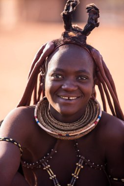Kamanjab, NAMIBIA --Sep 04 2019: ensesinde geleneksel saç stili ve kolyeleriyle Himba kadını. Güzel Himba kabilesi Namibya 'nın kuzeyindeki Namibya yerlileridir.