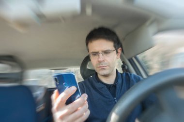 Adam araba kullanırken akıllı telefon kullanıyor..