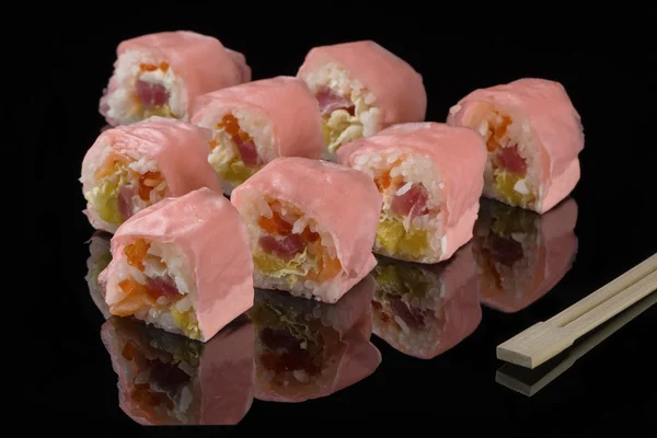 Розовые измельчители и деревянные палочки для суши на черном акриле — стоковое фото